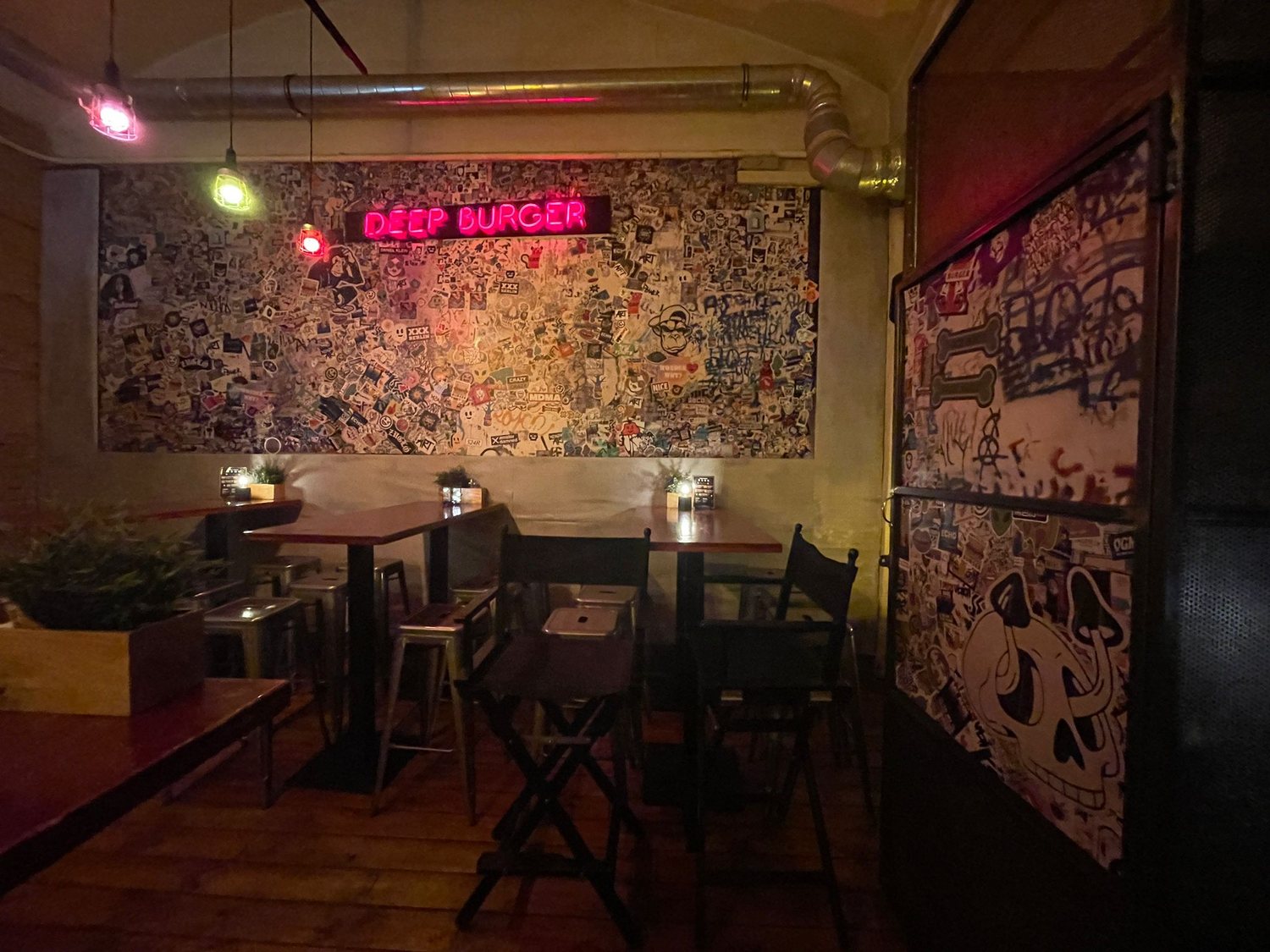 A burger bar interior under neon and a sticker wall